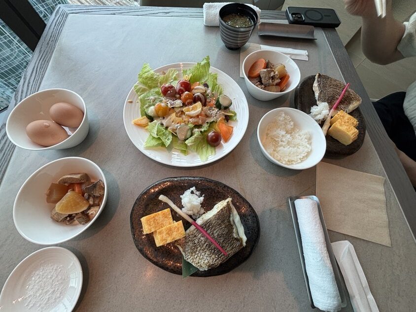 焼き魚と卵焼き、ご飯、サラダなどが並ぶ朝食のテーブル