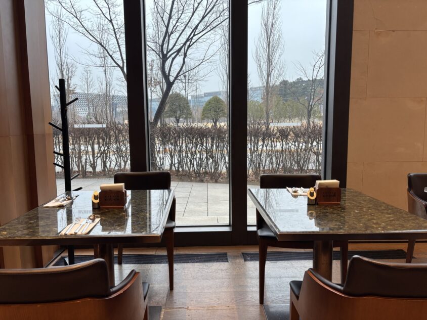 木のテーブルがあるエリアとGarden Kitchenの窓側席